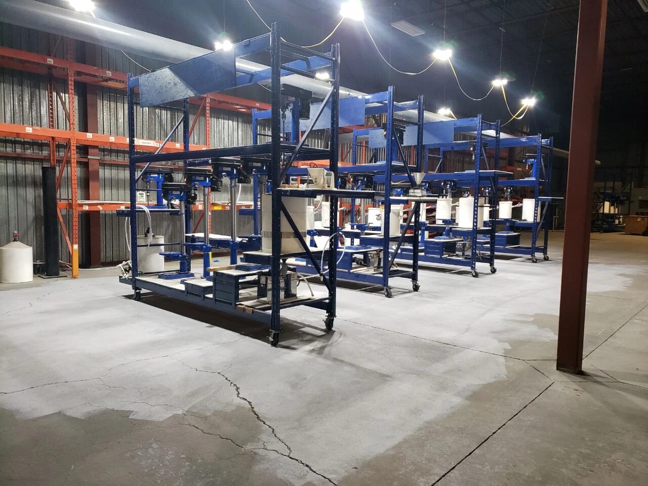 One rack of the pilot line: overhead stirrers over reactor tanks, with a feed hopper and dosing equipment
