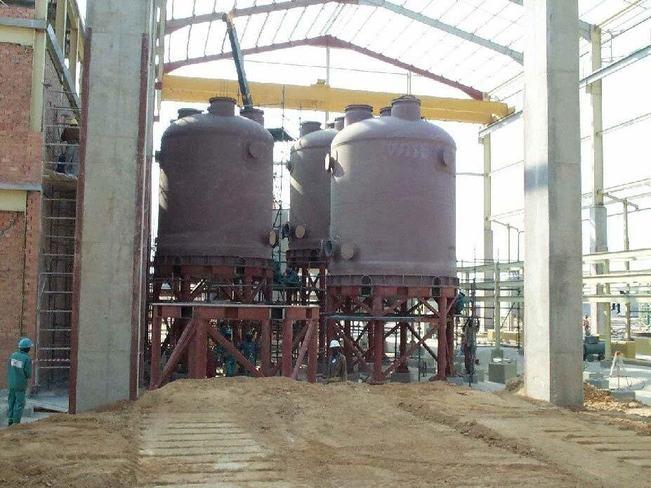 Three process tanks on steel stands inside a new building